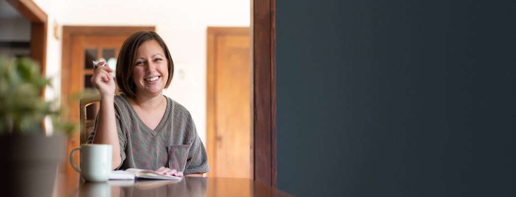 Regi Strauss sits at a table in her home